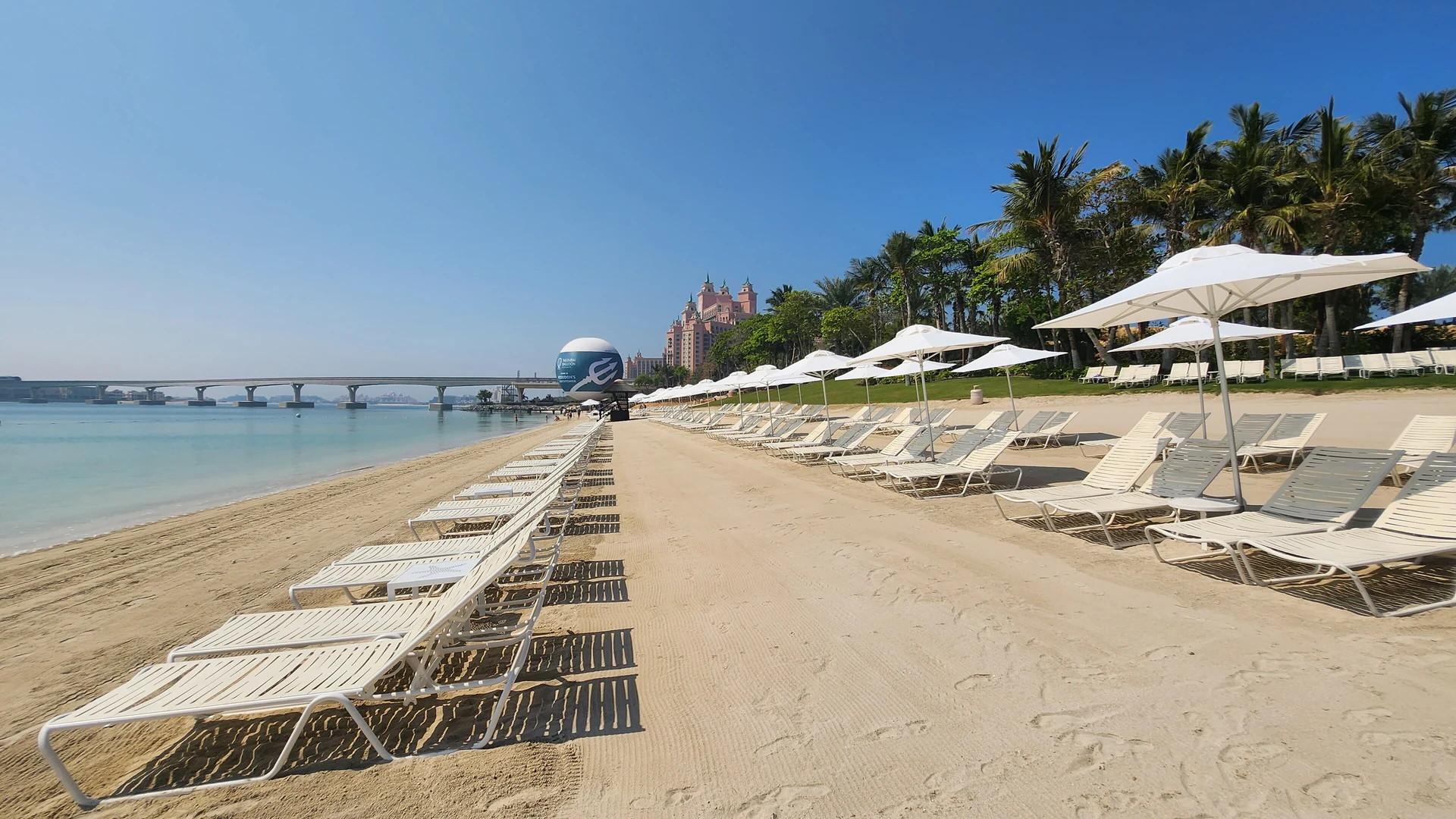 Aquaventure Beach at Atlantis, The Palm, Dubai, with loungers, the Palm Monorail bridge and the resort towers behind