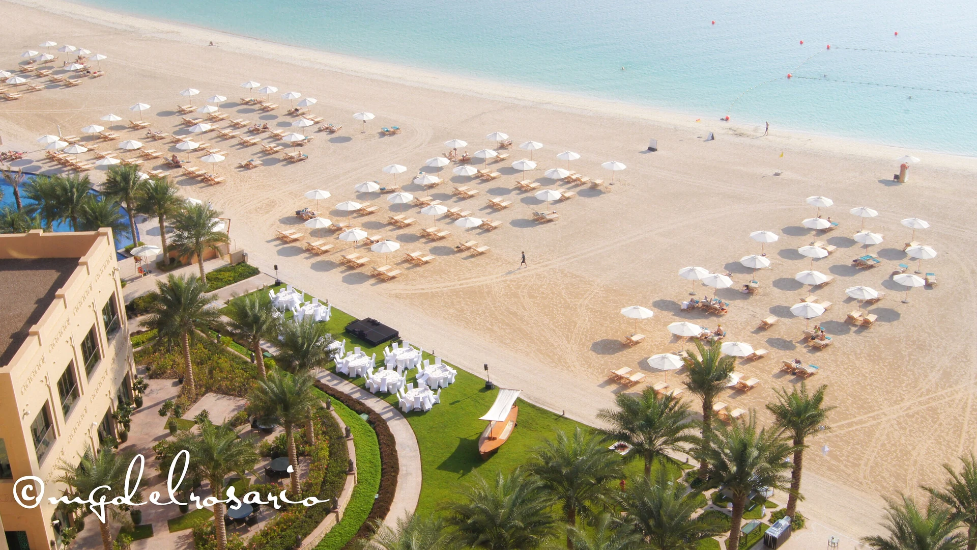 A beach resort on Palm Jumeirah with sun loungers, umbrellas and palm trees along the shoreline