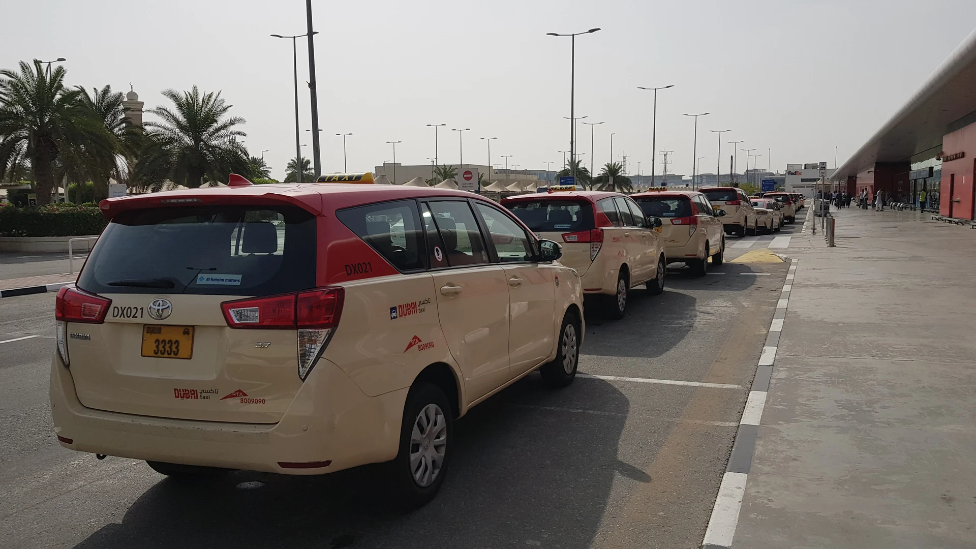 A queue of cream-and-red Dubai taxis outside Dubai International Airport Terminal 2