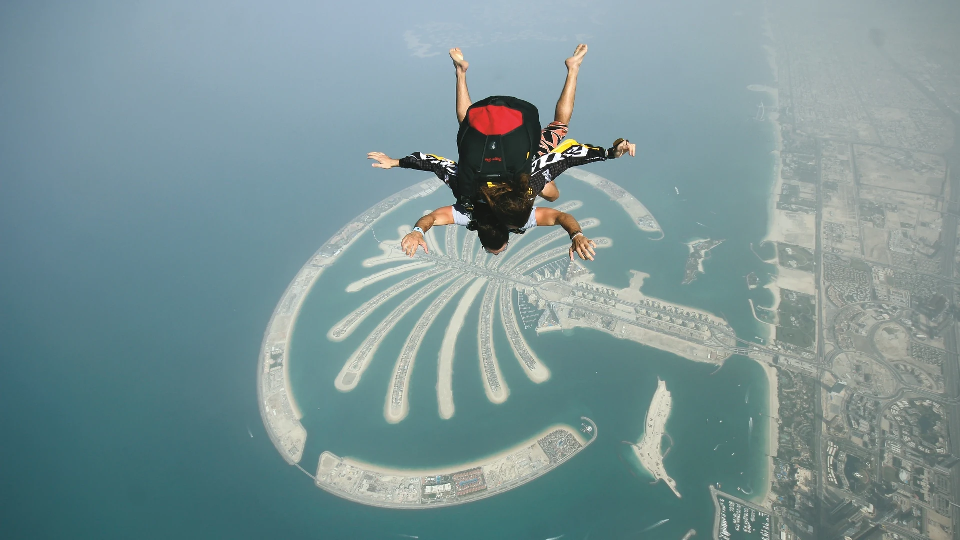 A tandem skydiver in freefall directly above the Palm Jumeirah archipelago in Dubai