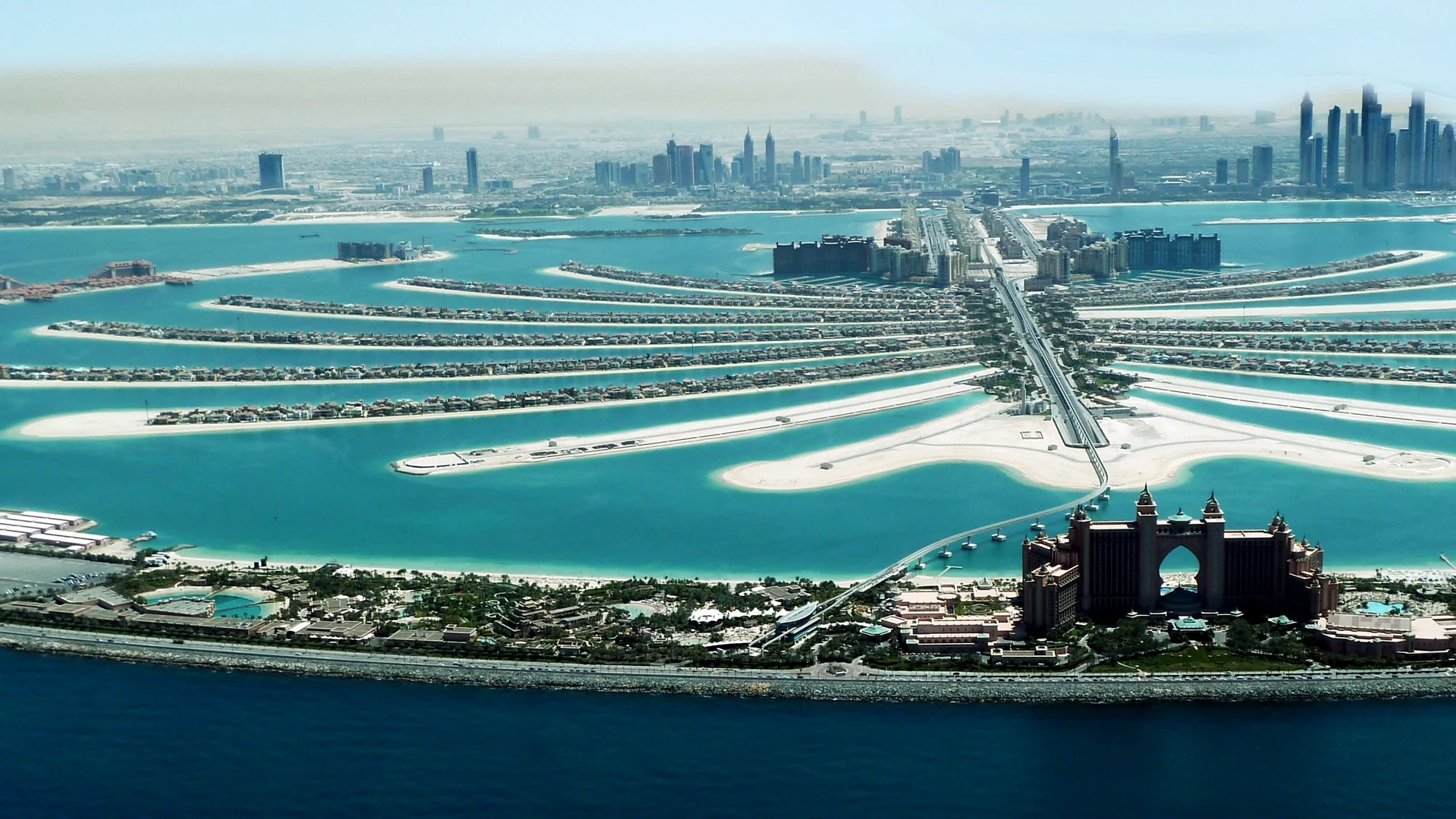Aerial view of Palm Jumeirah with Atlantis in the foreground and the Dubai Marina towers on the horizon